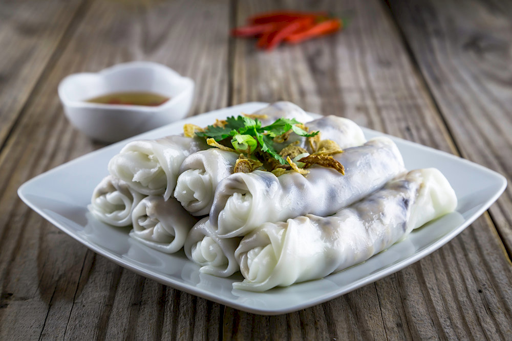 Steamed banh cuon, combining tender rice rolls with fragrant herbs and crunchy toppings 